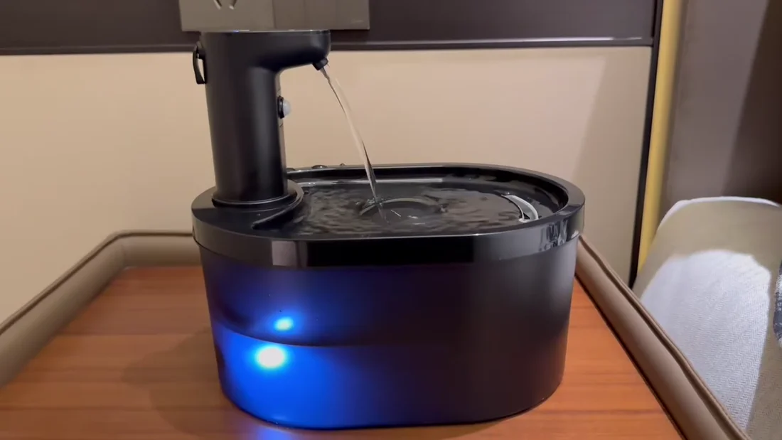 Real black cordless plastic fountain in operation with a blue illuminated translucent reservoir