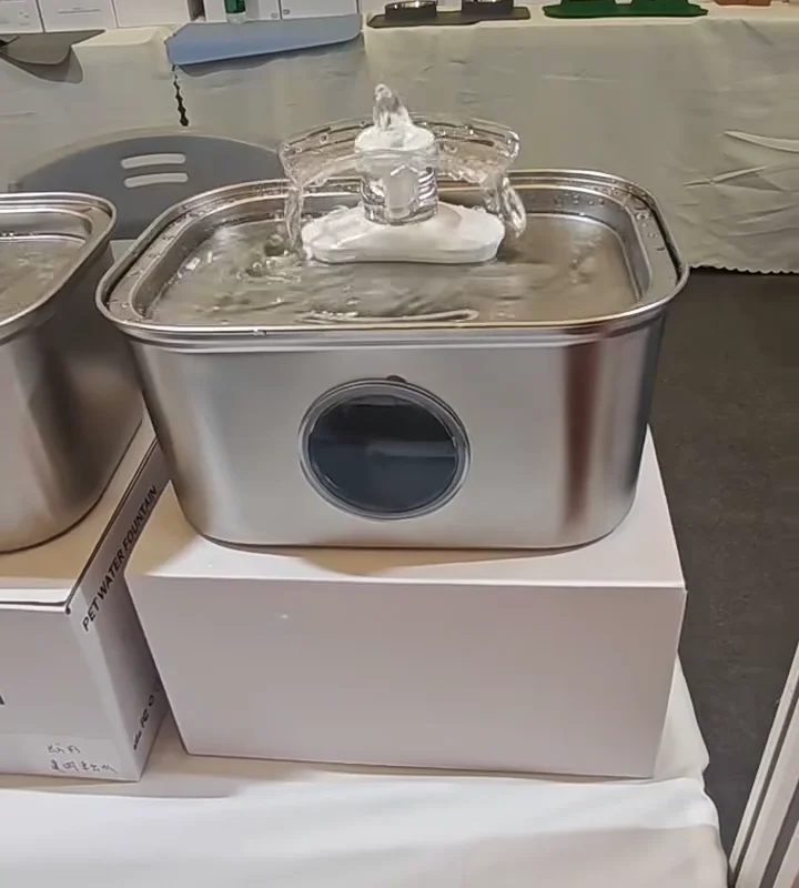 Water spreading from a visual-flow outlet into a stainless steel drinking tray in real product footage
