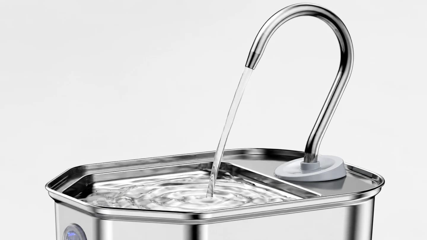 Close view of water falling from a plug-in steel fountain outlet onto the tray