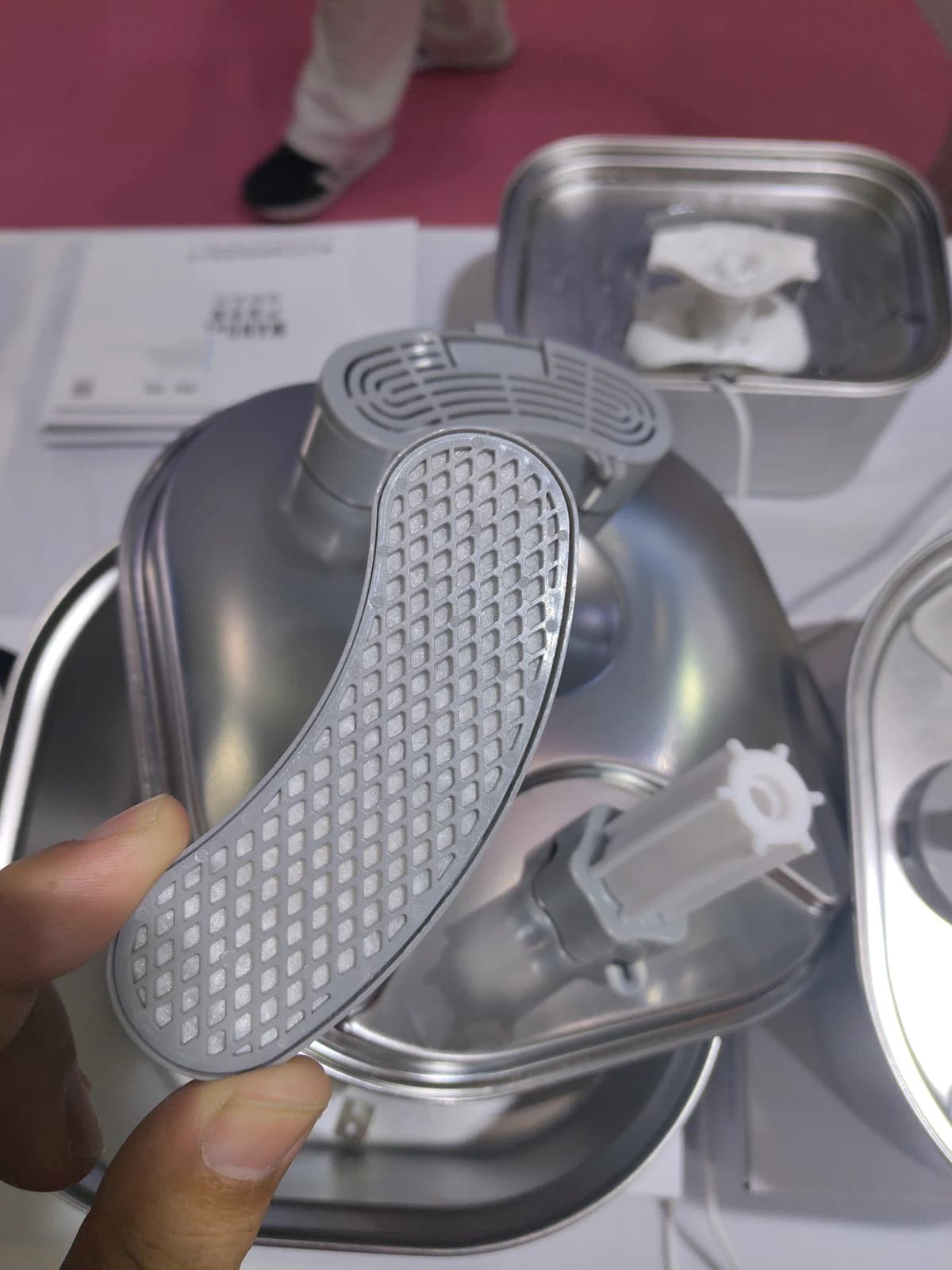 Hand holding a removable fountain filter above its open holder for visual inspection