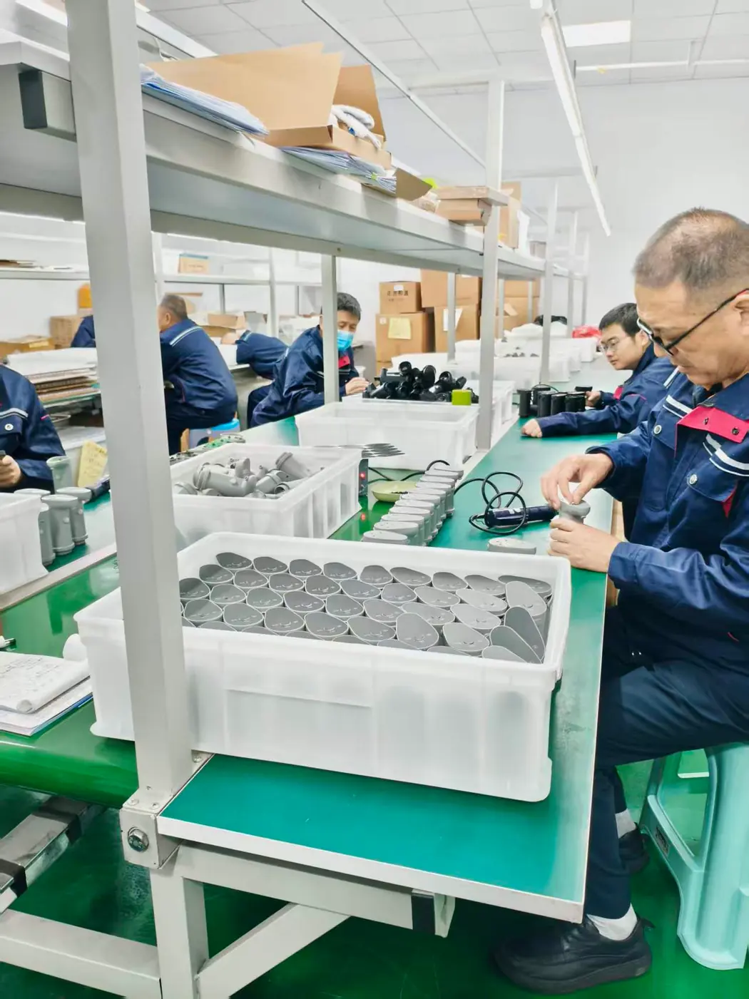 Workers checking fountain outlet components at assembly benches