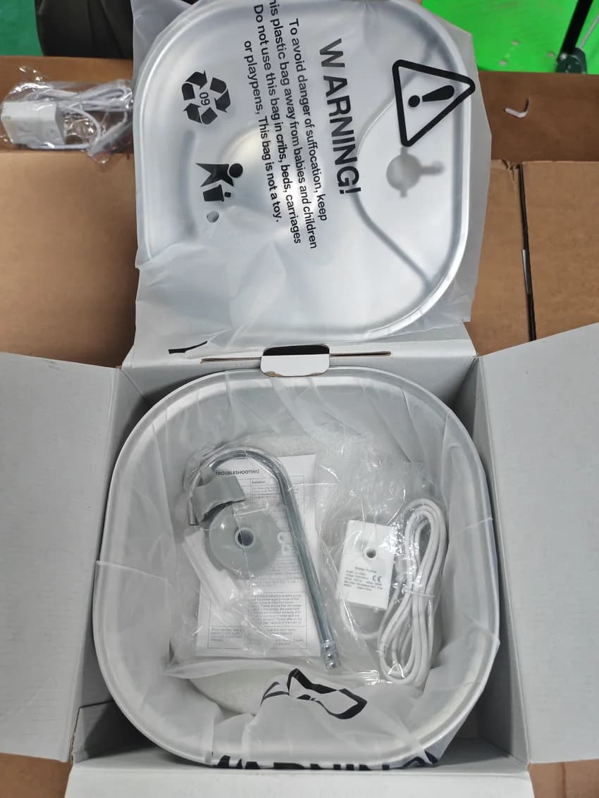 Real packed fountain with protected tray, pump, outlet parts and manual in an open carton