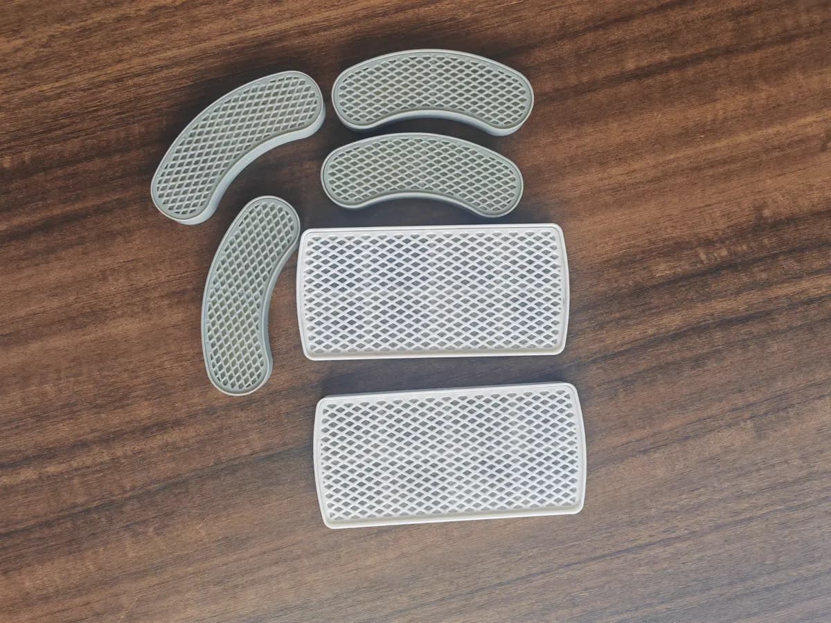 Crescent and rectangular Fountelio filter cartridges with perforated outer screens arranged on a wooden surface