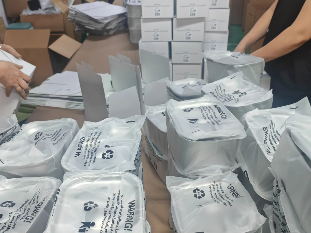 Protected stainless steel fountain bodies, folded boxes and workers preparing units for packing