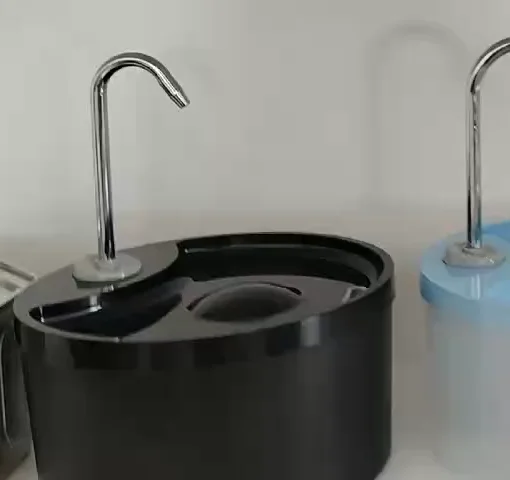 Close view of the curved metal spout and drinking tray on a black round plastic fountain