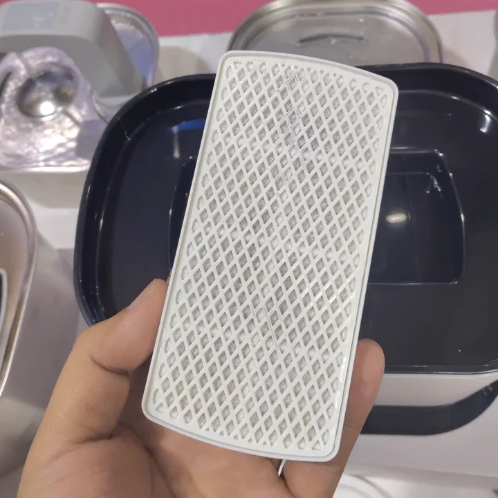 Crescent filter cartridge held above an open Fountelio cat water fountain for inspection